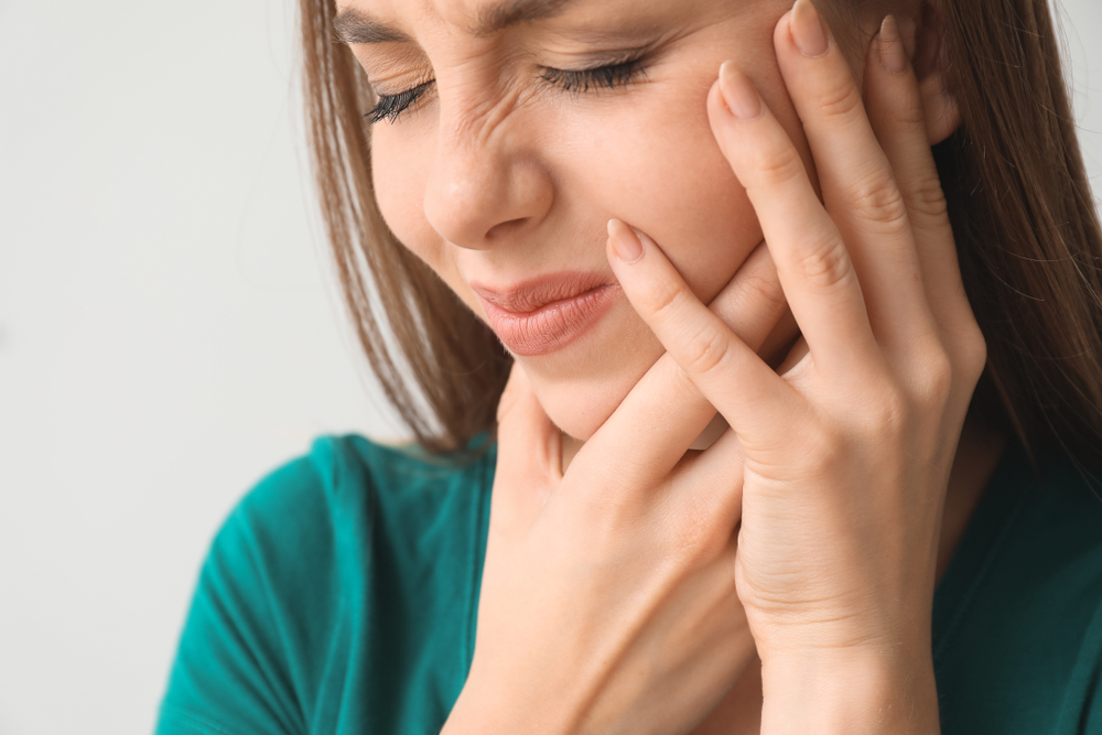 Young,Woman,Suffering,From,Toothache,Against,Light,Background,,Closeup