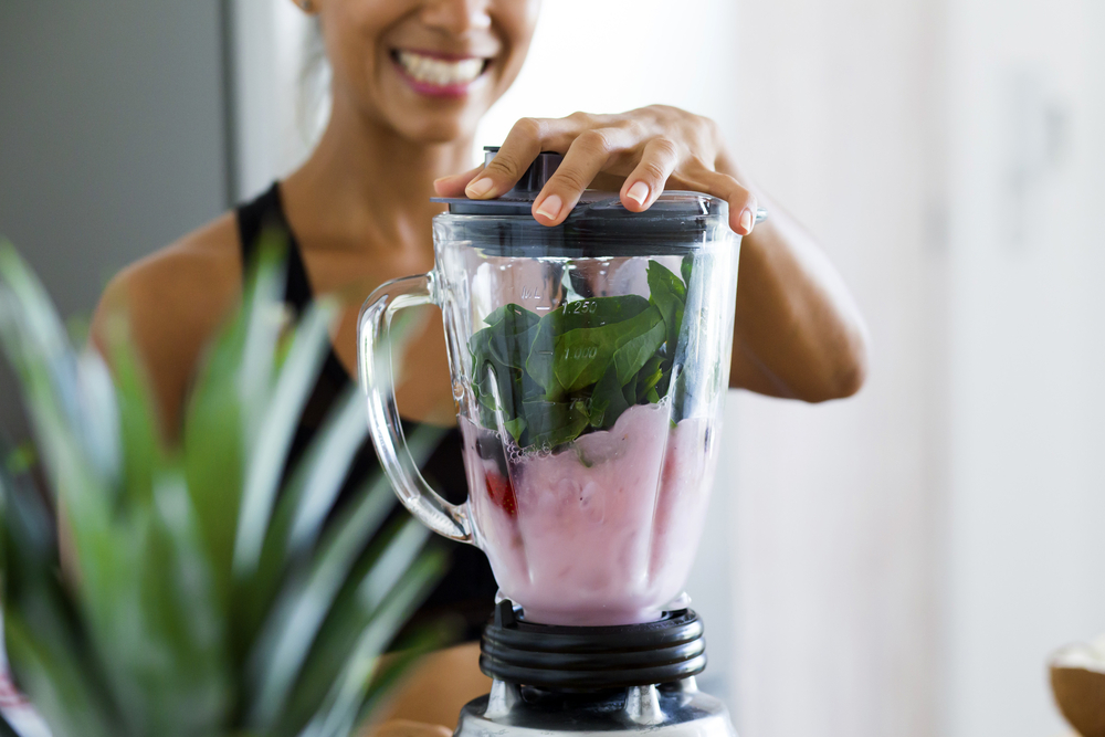 Woman,Blending,Spinach,,Berries,,Bananas,And,Almond,Milk,To,Make